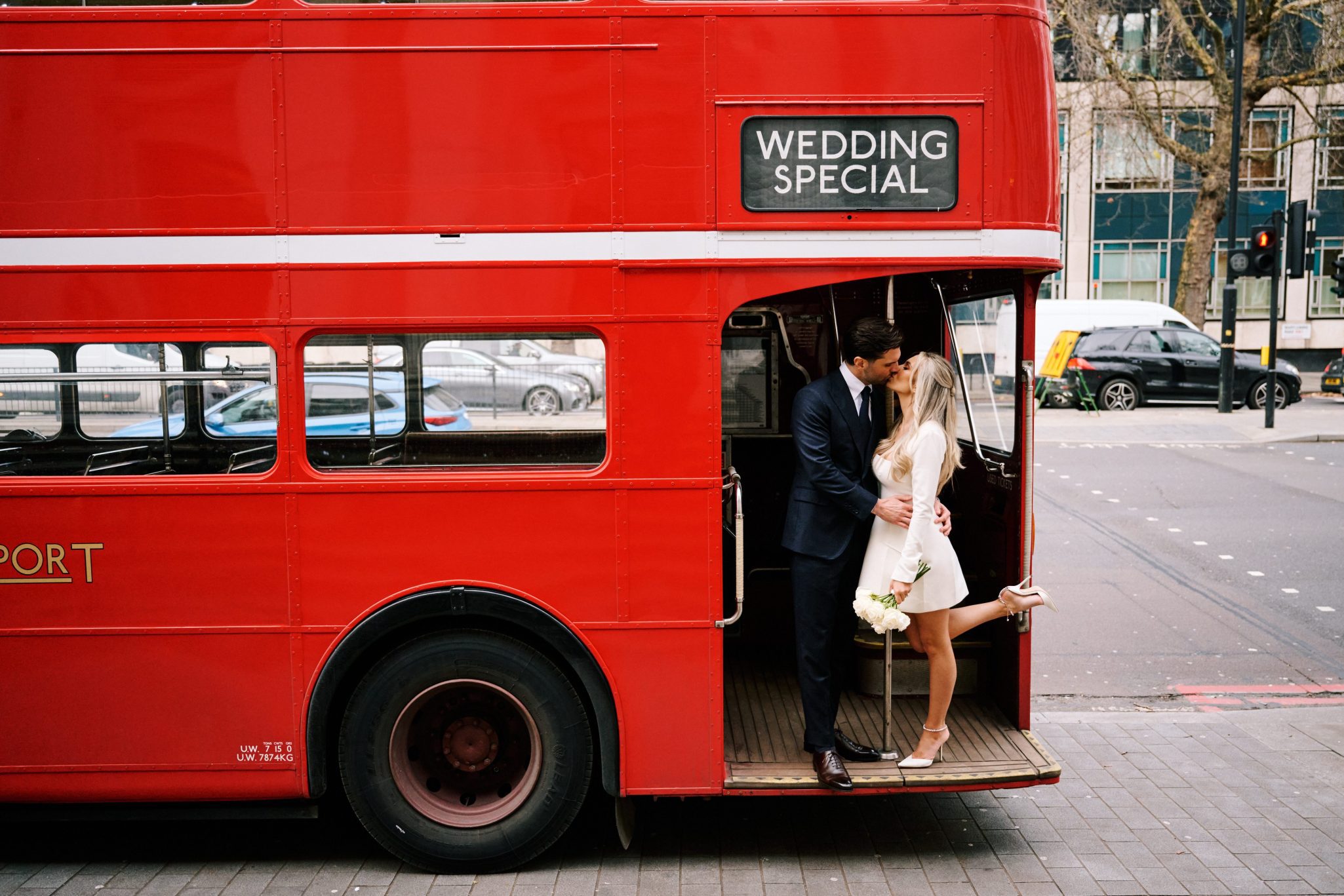 Bride and groom boarding a vintage red London bus after their intimate wedding ceremony