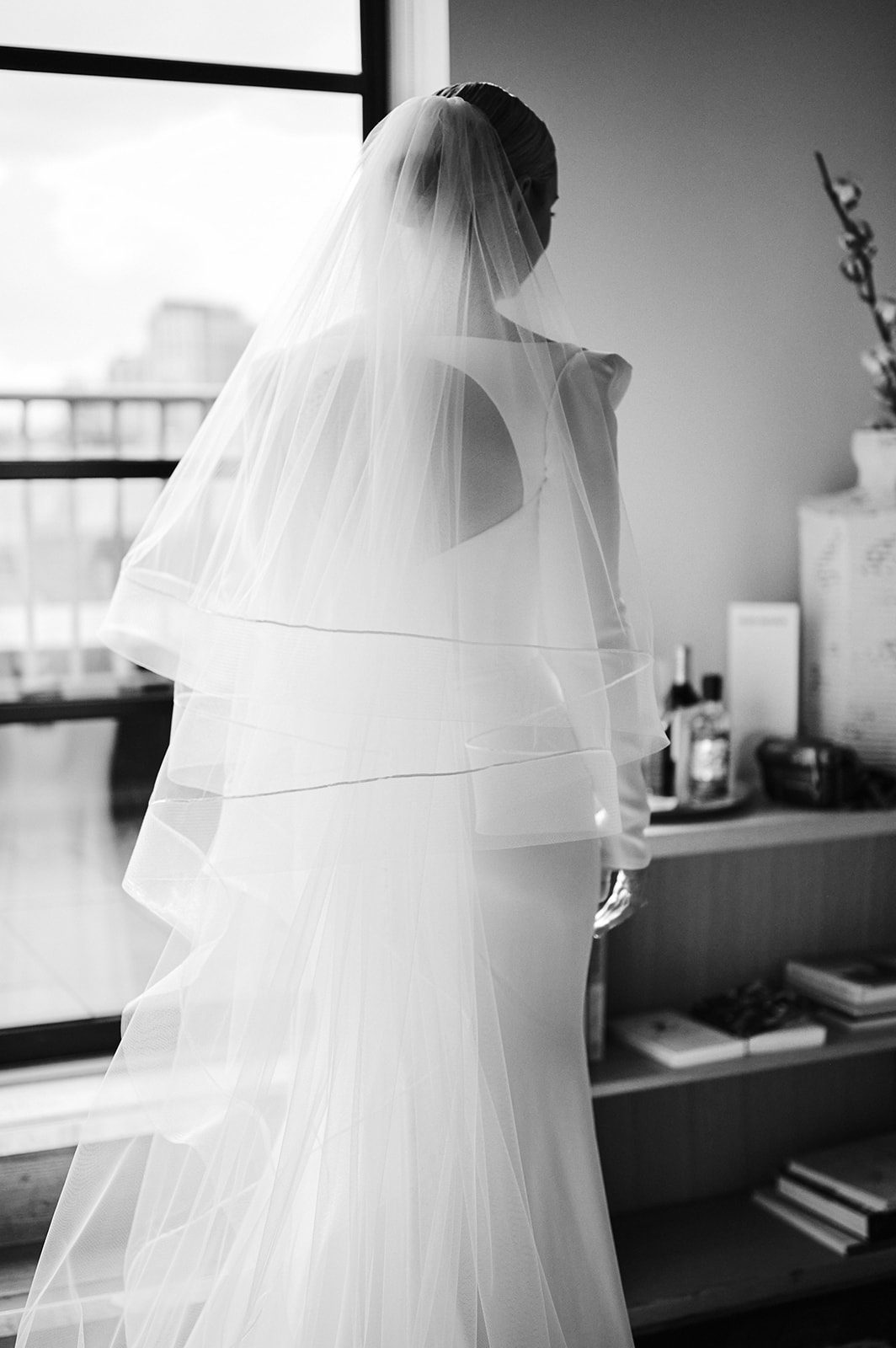 Bride looking out of the window in her wedding dress and veil