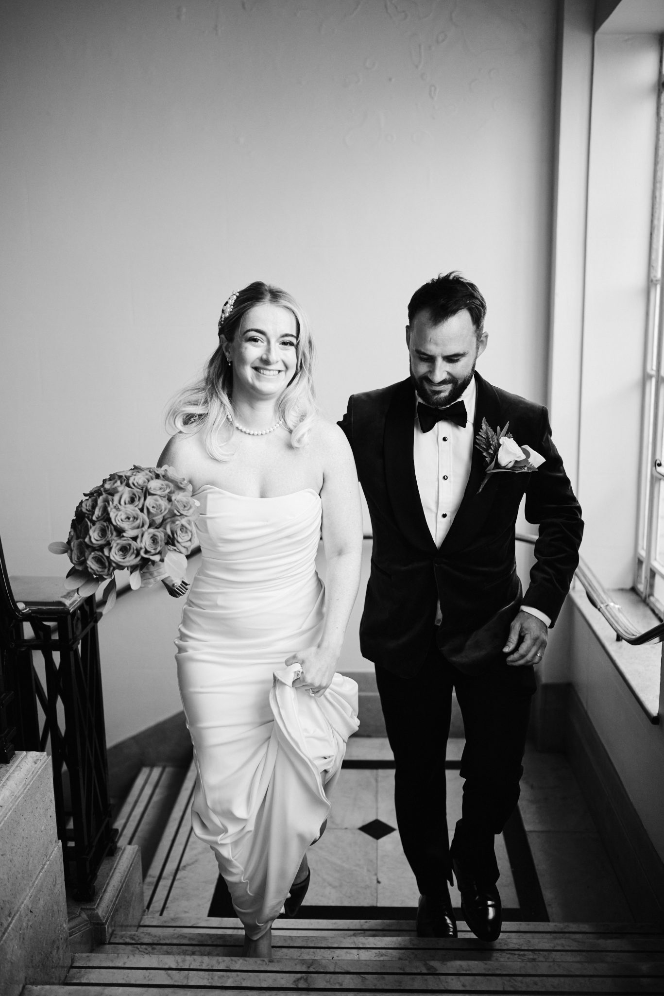 Bride and groom smiling as they walk down a staircase together