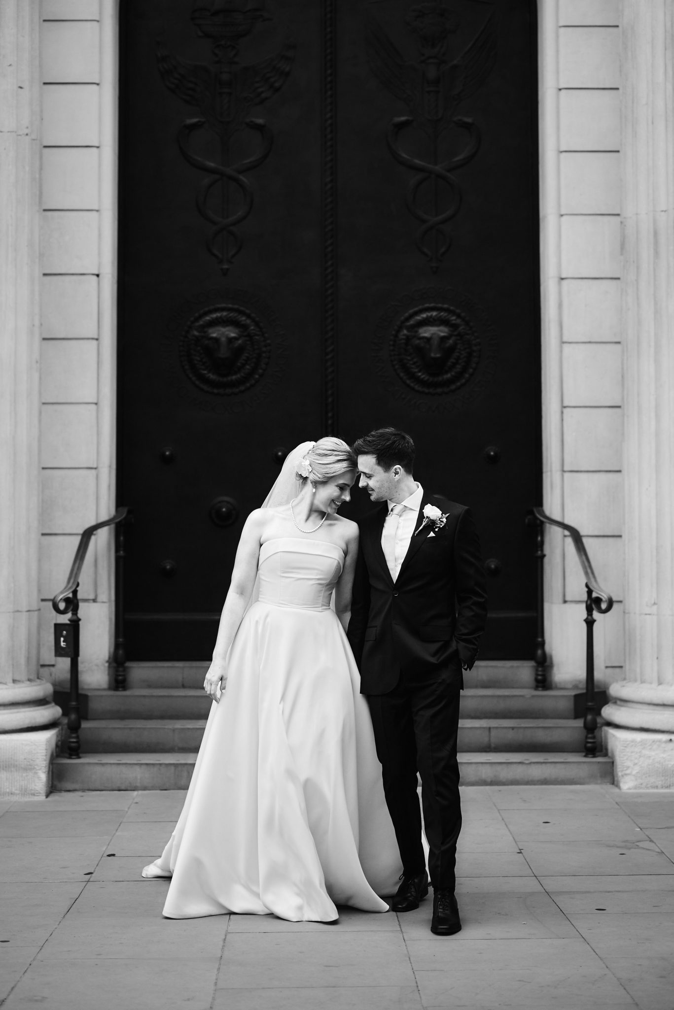 Bride and groom walking hand in hand in front of a grand doorway