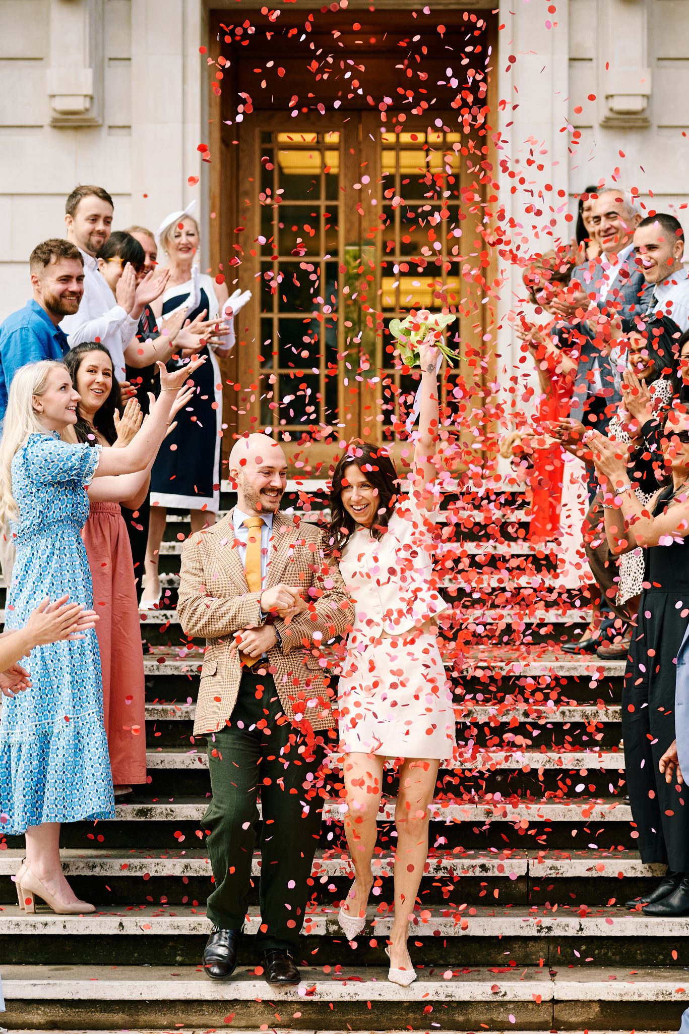 Bride and groom celebrating with confetti outside their London wedding venue